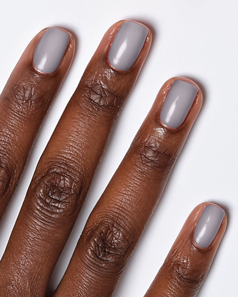 Model's hand showcasing Miracle Gel Supercharged Pinks nail polish in Fog-et Me Not, a soft gray shade.